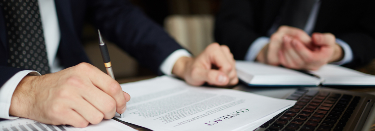 Closeup portrait of Clovis Law Group attorneys wearing black formal suit reviewing documents and signing contract during client meeting