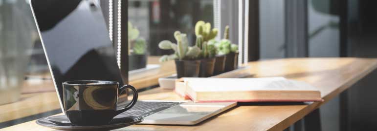 Work station with coffee and laptop at Clovis Law Group